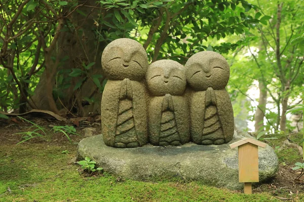 Small statues of baby buddhas surrounded by fresh green at the H Stock Picture