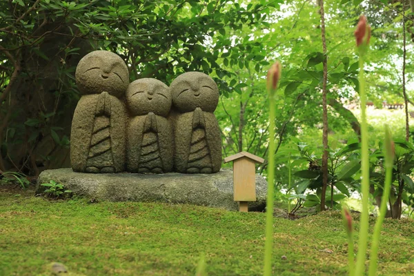 Small statues of baby buddhas surrounded by fresh green at the H Stock Picture