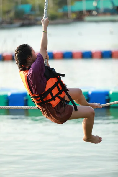 Jovem adolescente caminhando na corda apertada sobre a água — Fotografia de Stock