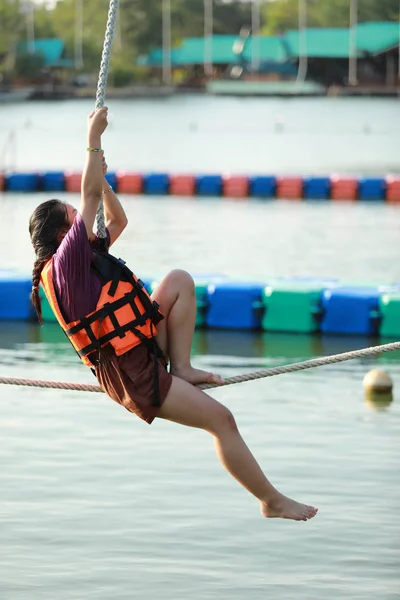 Jovem adolescente caminhando na corda apertada sobre a água — Fotografia de Stock