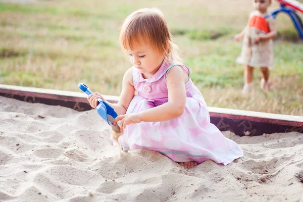 Kis lány játszik a homok-ban egy homokszóró láda — Stock Fotó