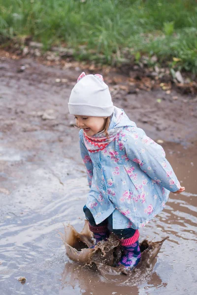 Klein meisje in de plas springen Stockfoto