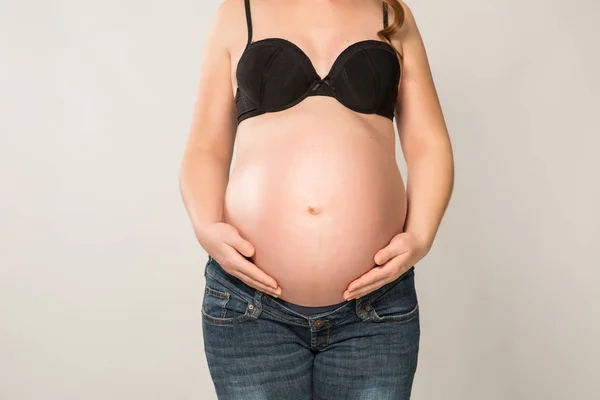 Gravid kvinna med händerna på magen — Stockfoto