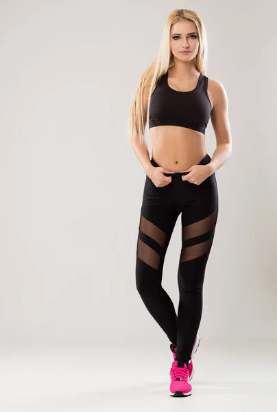 Blond och smal kvinnor i svart, träningskläder. — Stockfoto