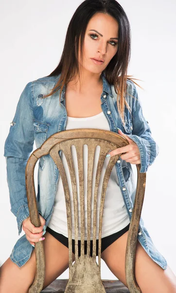Aantrekkelijke vrouwen dragen jeans jasje, zittend op de stoel. — Stockfoto