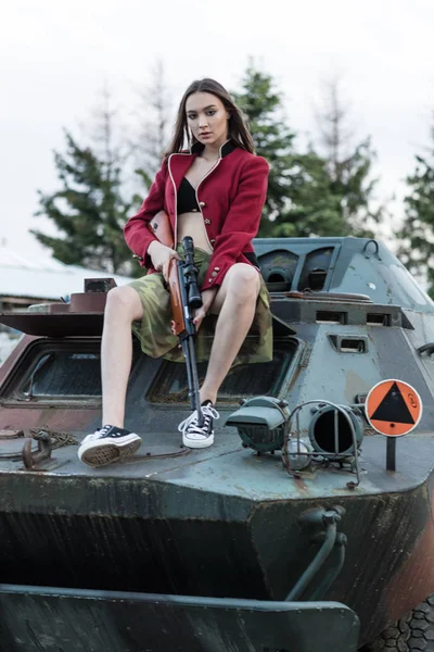 Modelo encantador con el arma sentada en el tanque . —  Fotos de Stock