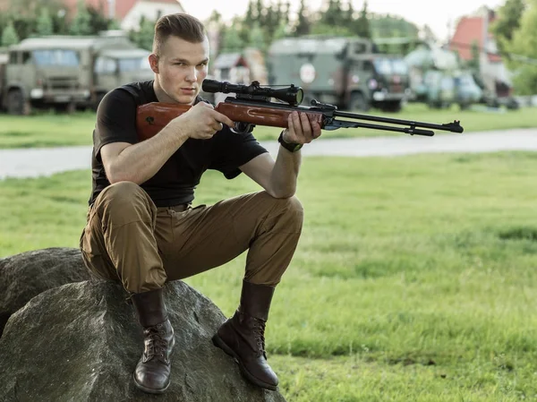 Sitzender Soldat mit Waffe Stockbild