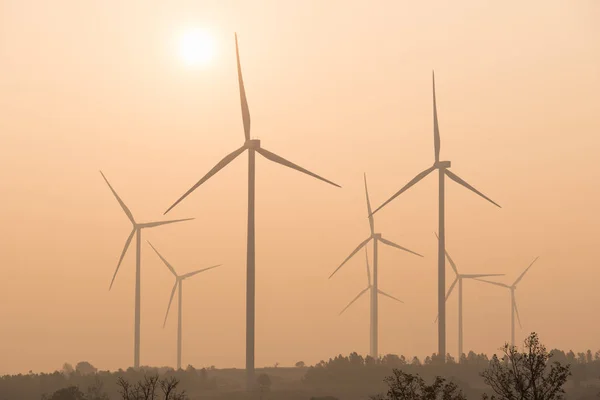 silhouette of wind turbines at sunset