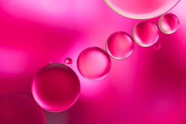 Gotas rosadas de aceite y burbujas de aire en el agua — Foto de Stock