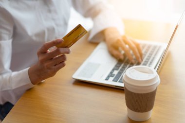 kredi kartı tutan ve online alışveriş için dizüstü kullanan kadın