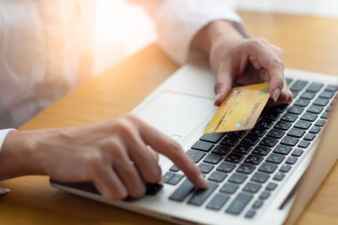kredi kartı tutan ve online alışveriş için dizüstü kullanan kadın