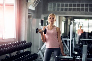Güçlü kadın spor salonunda dumbbells ile yapıyor
