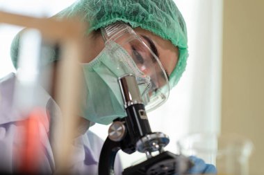 Genç Asyalı kadın bilim adamı bir laboratuvar, bilim ve kimya konseptinde mikroskopa bakıyor, tıp teknolojisi uzmanı.