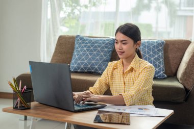 Güzel Asyalı iş kadını evinde dizüstü bilgisayarla çalışıyor, evden çalışıyor, iş konsepti yapıyor.