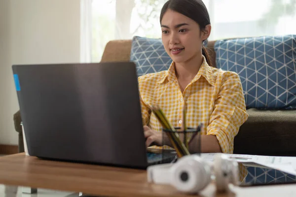 Beautiful young Asian businesswoman working with laptop at her house, work from home, business concept