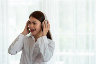 Genç Asyalı kadın portresi kulaklıkla müzik dinlemeyi seviyor, mutlu ve rahatlatıcı zaman.
