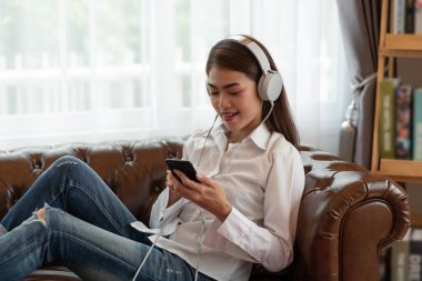 Genç Asyalı kadın portresi kulaklıkla müzik dinlemeyi seviyor, mutlu ve rahatlatıcı zaman.