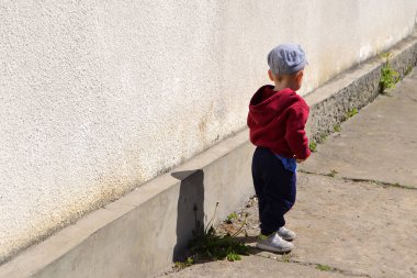 Çocuk duvarın yanında dikiliyordu.