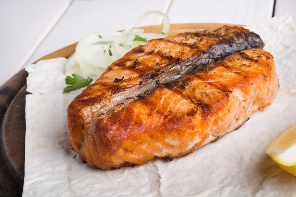 Fried salmon served on wooden board — Stock Photo, Image