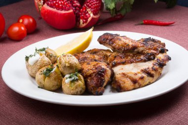 Yanında fırında patates olan kızarmış tavuk.