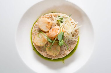 Deniz tarağı ve karides, kahverengi pirinç ile servis edilir.