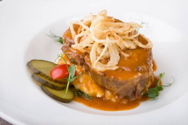 Dilimlenmiş salatalık turşusuyla servis edilen patates püresiyle sığır eti.