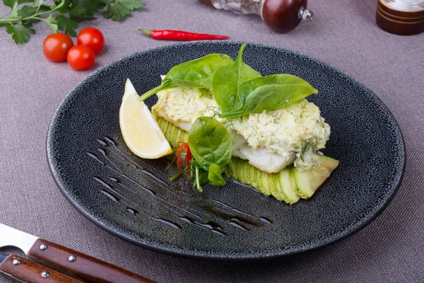 Cooked white fish fillet served with grilled zucchini and lemon