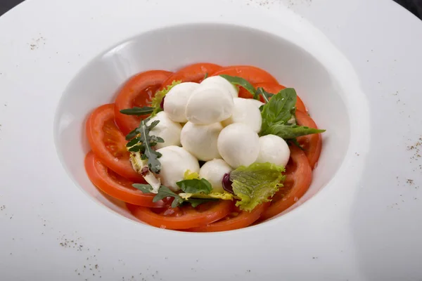 White buffalo mozzarella cheese with red tomatoes set on a table