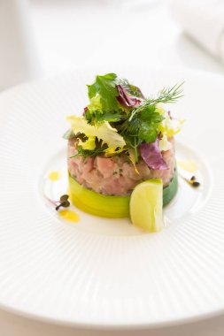 Taze pişmiş tartar, büyük beyaz bir tabakta limon ile servis edilir.