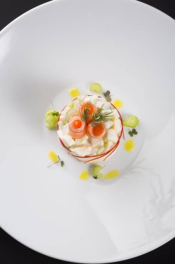 Beyaz kasede servis edilen zarif tütsülenmiş somon salatası.