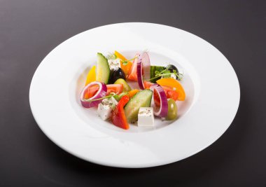 Beyaz tabakta servis edilen zarif sebze Yunan salatası