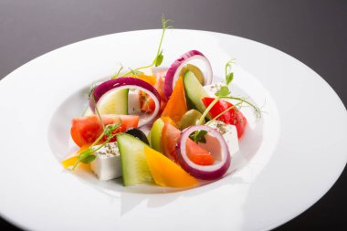 Beyaz tabakta servis edilen zarif sebze Yunan salatası