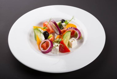 Beyaz tabakta servis edilen zarif sebze Yunan salatası