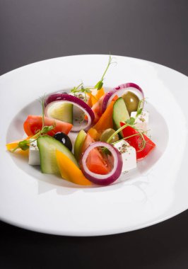 Beyaz tabakta servis edilen zarif sebze Yunan salatası