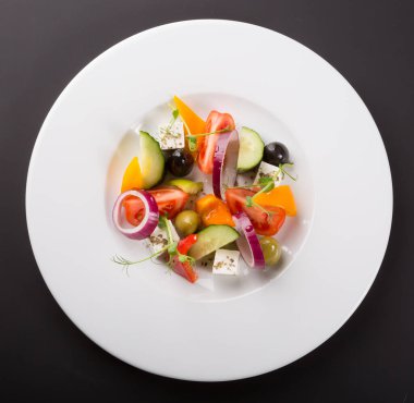 Beyaz tabakta servis edilen zarif sebze Yunan salatası