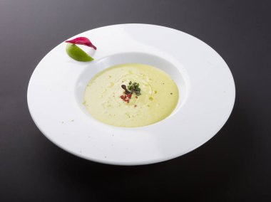 Yeşil kremalı avokado çorbası ve limonlu beyaz kase.
