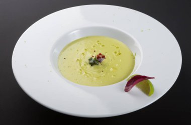 Yeşil kremalı avokado çorbası ve limonlu beyaz kase.