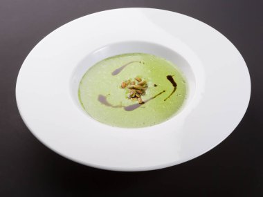 Beyaz tabakta yeşil kremalı sebze çorbası.