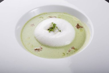 Beyaz tabakta yeşil kremalı sebze çorbası.