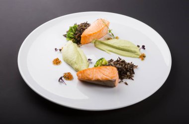 Beyaz tabakta mantarlı ve sebzeli kızarmış somon.