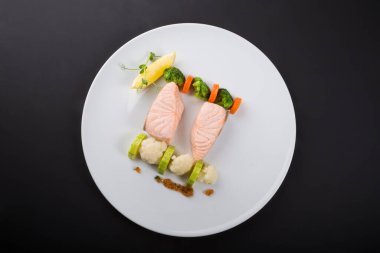 Brokolili haşlanmış somon ve beyaz tabakta karnabahar.