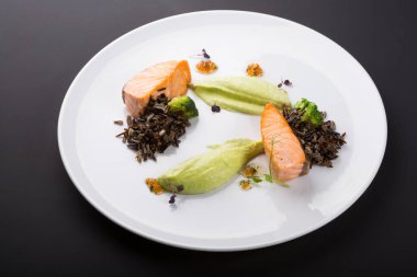 Beyaz tabakta mantarlı ve sebzeli kızarmış somon.