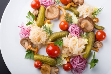 Bir tabakta marine edilmiş sebze ve mantar servis edilir.