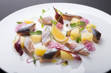 Soğan ve limonla servis edilen tuzlu ringa filetosu.