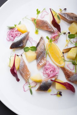 Soğan ve limonla servis edilen tuzlu ringa filetosu.