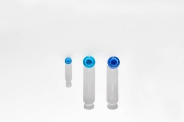 Farklı tonlarda mavi suyu olan bir test tüpü. Beyaz bir arka plana gölge düşürürler. Test tüpü farklı boyutlarda. Yukarıdan görüntüle.