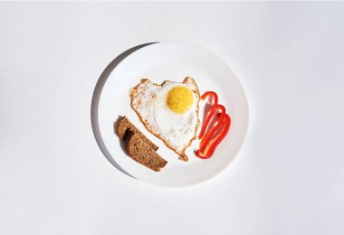 Yağda yumurta, barış ekmeği ve beyaz tabakta kırmızı biber dilimleri. Ev kahvaltısı. Beyaz arka planda var..