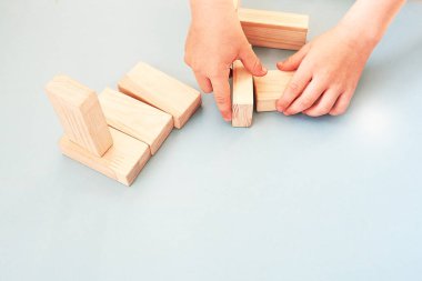 Çocuk mavi arka planda tahta bloklarla oynuyor. Yukarıdan bak. Çocuk elleri