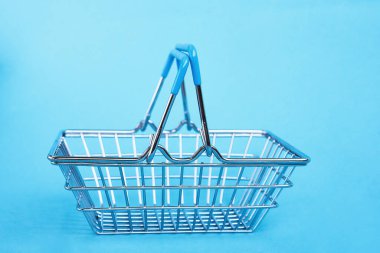 Mavi arka planda süpermarket alışveriş sepetinin yan görüntüsü. Kara Cuma indirim konsepti. Boşluğu kopyala.