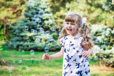 Kız sabun köpüklerine bakıp gülüyor.